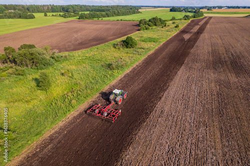 tractor cultivating a field with a harrow