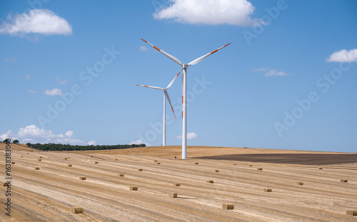 wind turbines in a field with straw bales