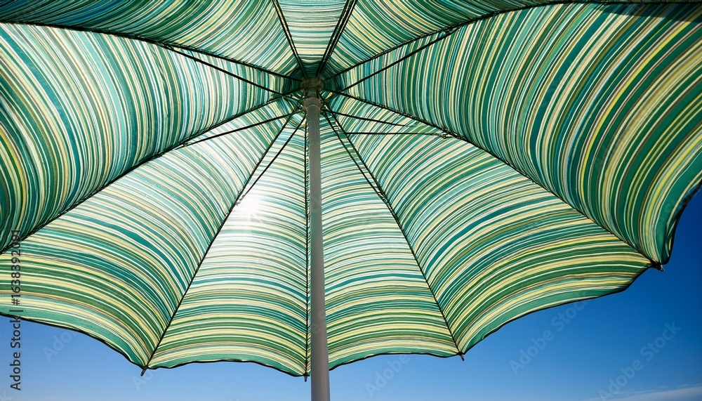 green striped umbrella against clear blue sky summer outdoor shade beach relaxation