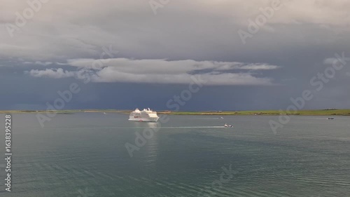kirkwall united kingdom aug 9 202 Cruise Ship Sailing Under Stormy Sky Near Scenic Green Coastline