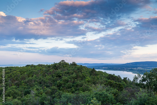 View of green hills and lake under cloudy sky, panoramic view of Lake Balaton from the Tihany lookout in Hungary,