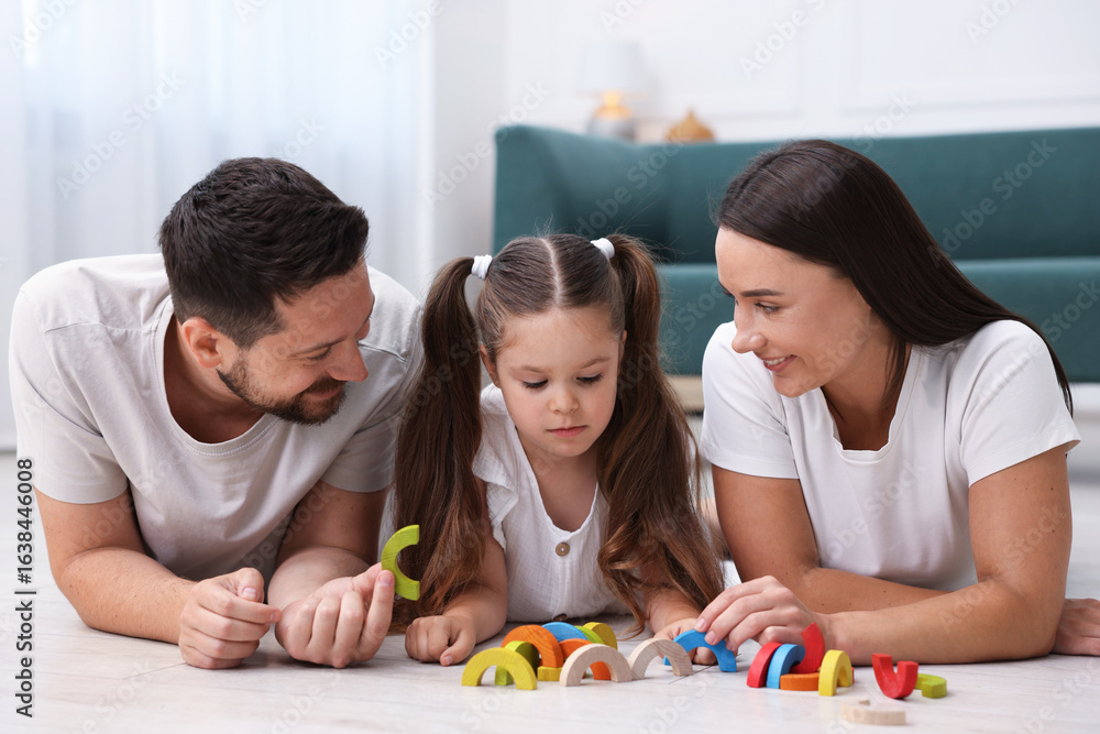 Fototapeta premium Parents and their daughter playing with toys on warm floor at home. Heating system