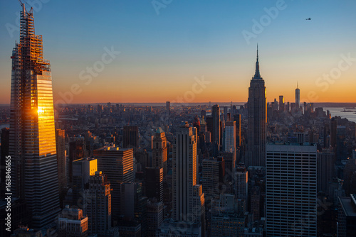 Foto Manhattan skyline during golden hour showing Empire State Building modern skyscr