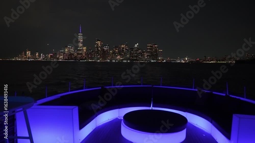 A stunning night scene showcasing the NYC skyline from a luxury yacht, illuminated by colorful lights