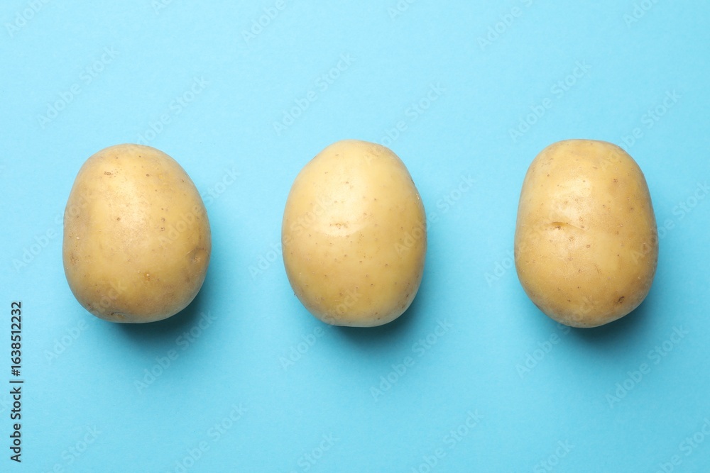 Fototapeta premium Fresh raw potatoes on light blue background, top view