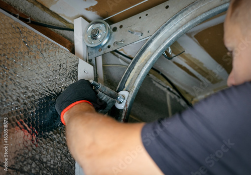 Canvas Print Close-up of a worker attaching rollers to the metal tracks of a garage door during installation or repair
