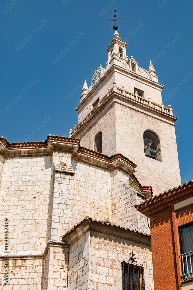 Fototapeta premium Tordesillas, Valladolid, Spain – View of the church bell tower rising above the historic town under a clear blue sky.
