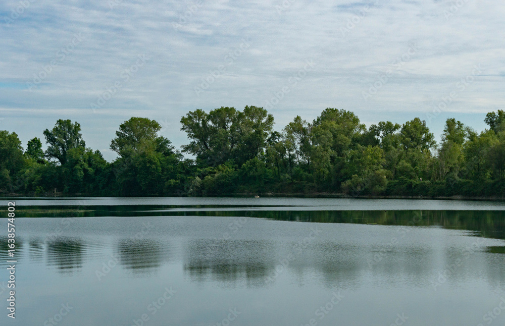Fototapeta premium Countryside Lake with Man Fishing in Distance