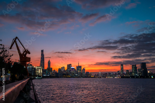 The urban skyline of the Huangpu River in Shanghai, China, under a beautiful sunset.