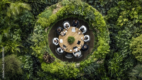 Aerial view of a meeting at a round table surrounded by lush, green foliage