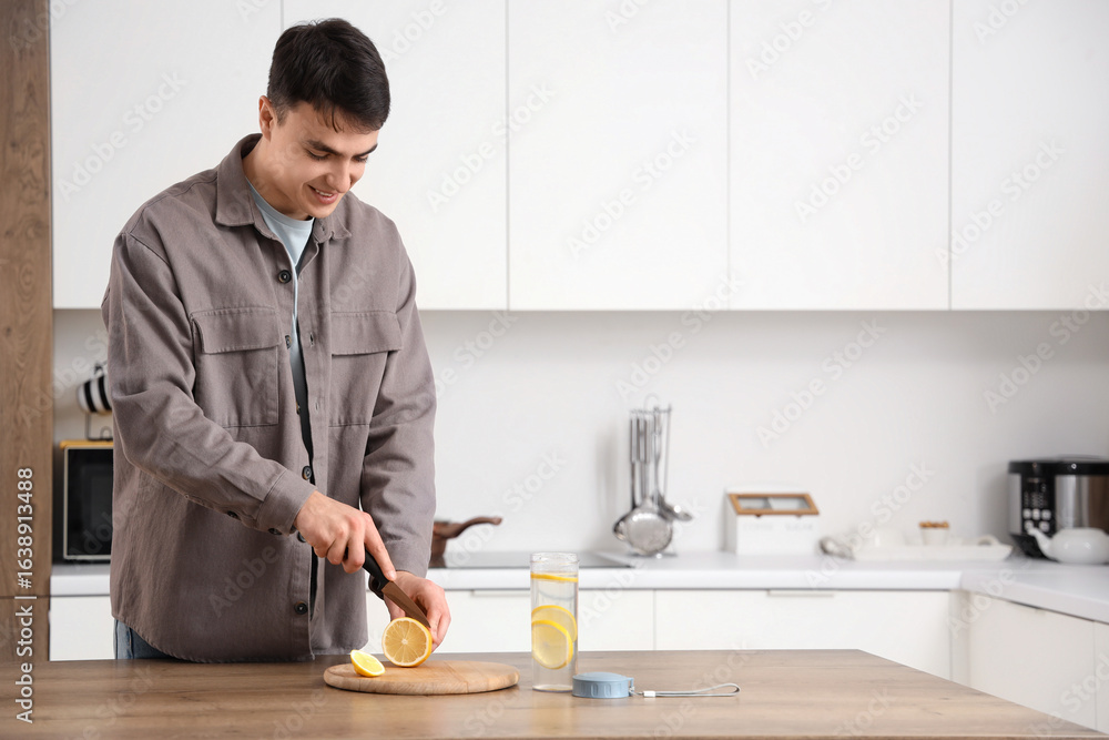 Handsome young man cutting lemons for infused water at home Handsome young man cutting lemons for infused water at home