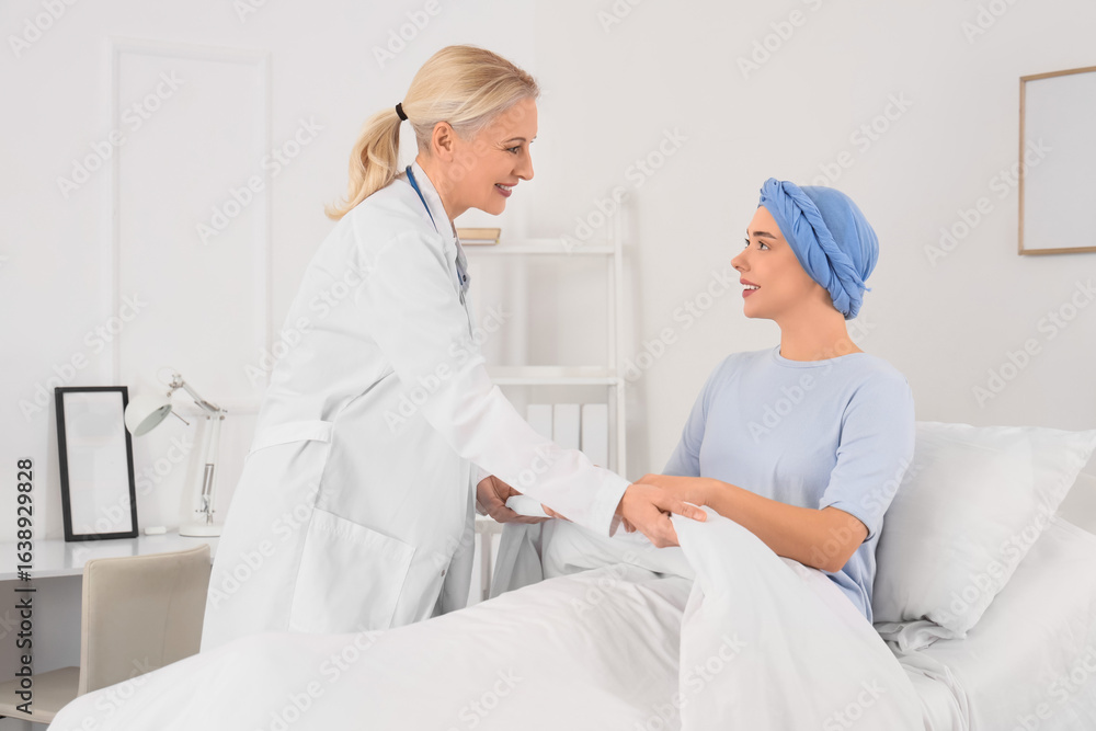 Obraz premium Doctor covering young woman after chemotherapy with blanket in hospital room. Brain cancer concept