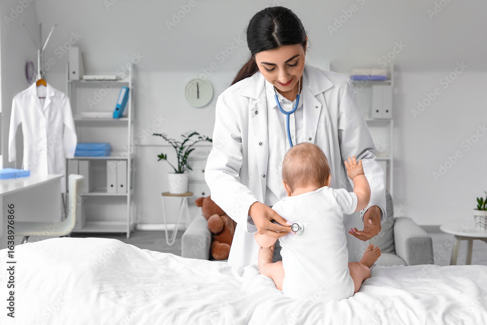 Obraz premium Female pediatrician with stethoscope listening to baby in clinic