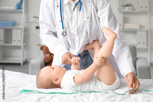 Female pediatrician measuring baby on couch in clinic