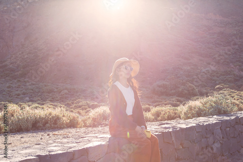 A young beautiful vietnamese woman wearing a hat and sunglasses contemplating the Mount Teide, Canary Islands, Spain.