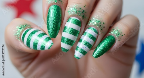 Close-up of woman's hand showing festive green and white striped nail art design