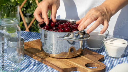 Fotografija A Caucasian woman prepares a cherry concoction under the sun, evoking Lammas fea