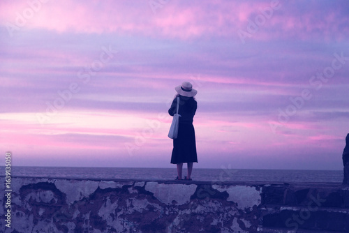 A young vietnamese woman on the beach at night alone in Tenerife, Canary Island, Spain, about the meaning of living.