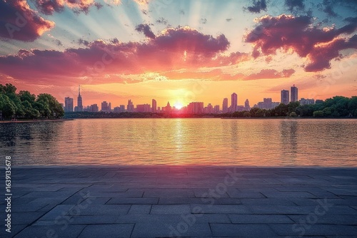 Vibrant sunset over a calm city skyline reflecting on a large body of water with dramatic clouds and peaceful atmosphere