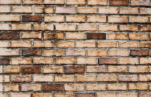 Close-up of a weathered brick wall with varied brown and tan bricks