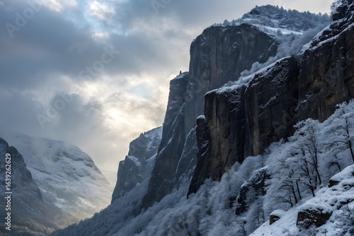 Wallpaper Mural Dramatic snow covered mountain cliffs with moody sky and sunlight breaking through clouds Torontodigital.ca