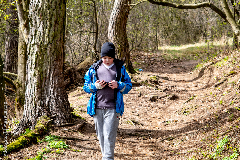 Naklejka premium Boy walking in spring forest trail