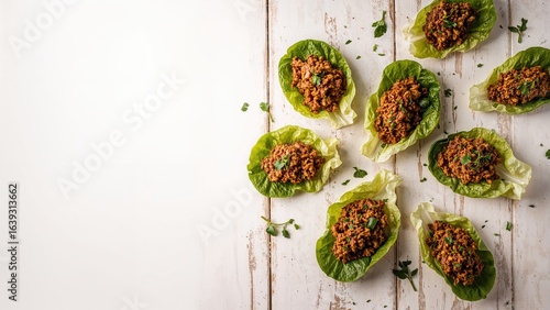 Fresh lettuce leaves filled with seasoned minced pork, a well-liked starter in Asian dishes, arranged on a wooden tabletop, viewed horizontally from above.