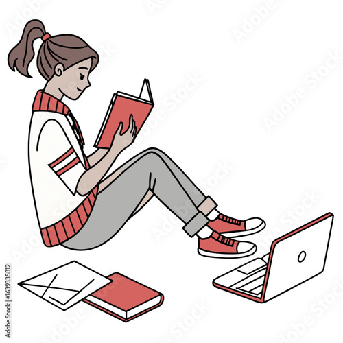 Young woman sitting and reading a book with a laptop nearby and another book on the floor