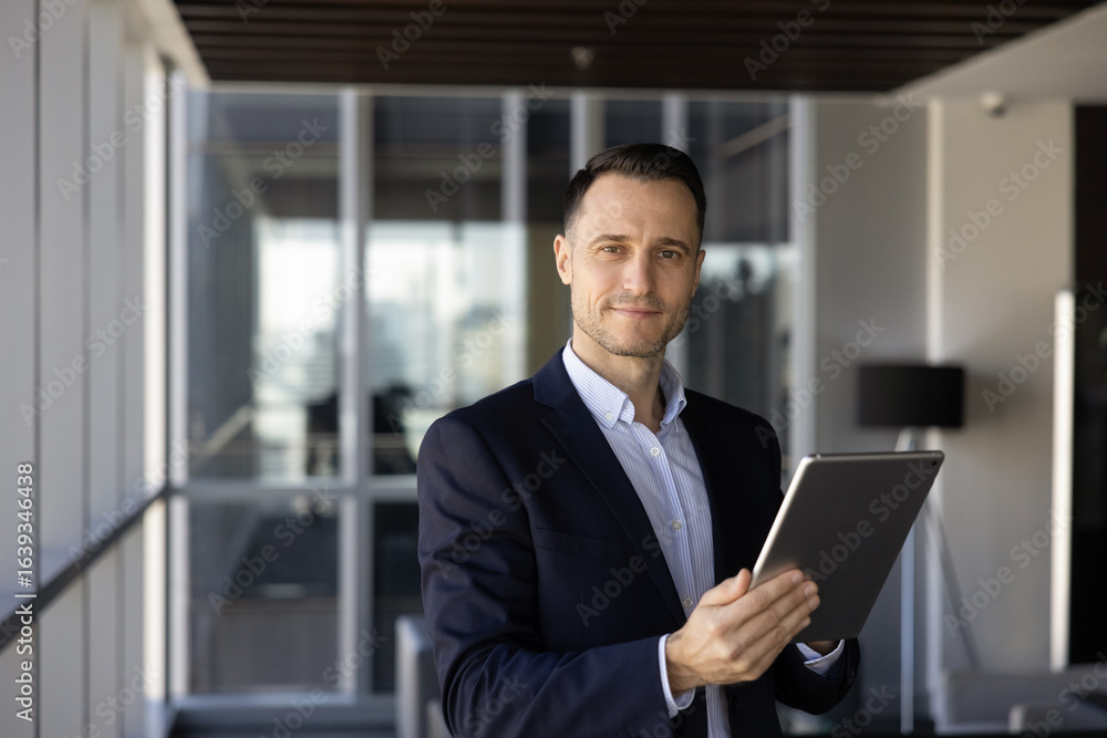 Positive confident young Hispanic CEO man posing for portrait with digital gadget in office hall, looking at camera, holding tablet. Successful male investor, legal, financial advisor portrait Positive confident young Hispanic CEO man posing for portrait with digital gadget in office hall, looking at camera, holding tablet. Successful male investor, legal, financial advisor portrait