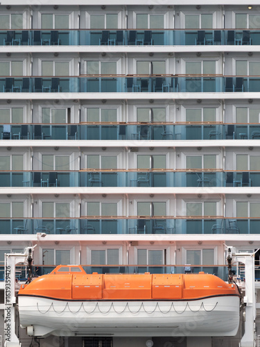 Lifeboat against rows of passenger cabins on big cruise ship at day