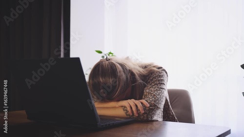 Upset tired woman working on laptop, sitting at table in room, sad girl unemployed freelancer. head sadly falls on hands. depression, bad stress mood fatigue, lack of money. Person looking for job