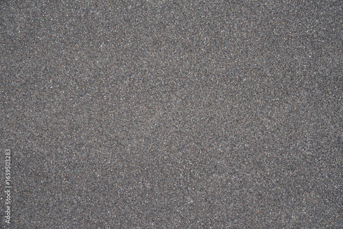 Fotografie Seamless uniform dark gray stone granules texture, gravel aggregate surface back