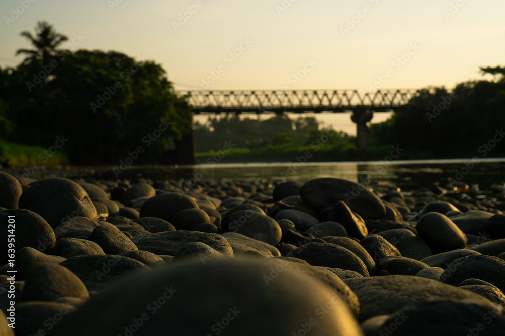Fototapeta premium Pebbled Riverbank Under Soft Sunset Light