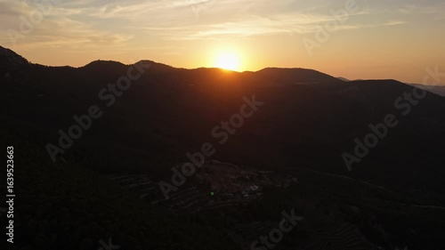 Wallpaper Mural Aerial drone video capturing mountain peaks in Spain during sunset, with golden sunlight illuminating the horizon above dark forested slopes. Torontodigital.ca