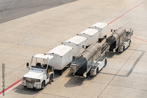 This is an airport baggage and cargo tractor pulling a train of luggage carts and container dollies.