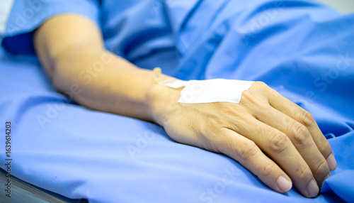 Arm with IV drip rests on blue hospital bed, conveying modern healthcare and patient recovery concepts