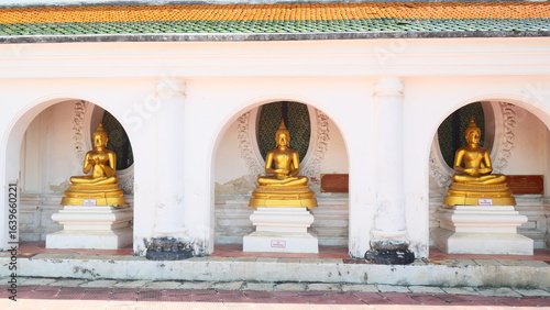 Quadro su tela Three golden Buddha statues in a row under arched alcoves at a temple