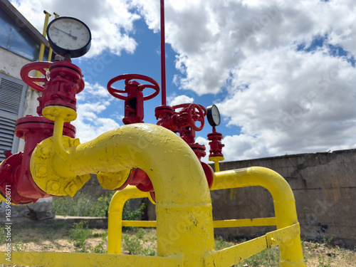 A bright yellow pipe featuring red valves and gauges attached to it