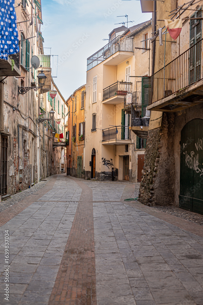 Fototapeta premium Medieval houses in Albenga, characterized by narrow alleys called carrugi, and arches, support bridges between the houses in the historic center, in the province of Savona, Liguria.