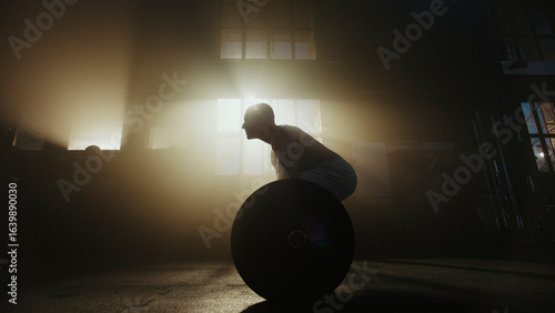 Foto Determined athlete lifting weights in smoky gym with sunlight beams
