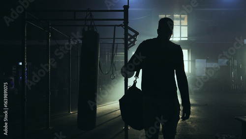 Fototapeta Naklejka Na Ścianę i Meble -  Boxer entering boxing gym with sports bag at night