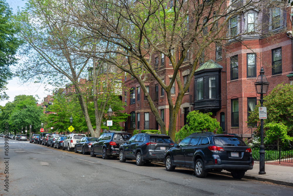 Obraz premium Quiet residential street lined with parked cars and historic red-brick townhouses in Boston, Massachusetts, USA