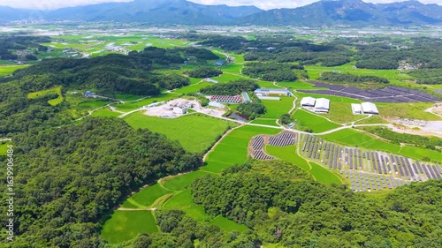 Aerial Drone View of Highway and Cars Driving Through Green Fields and Forest, with Vast Summer Landscape, Blue Sky, and Clouds for a Healing Scenery