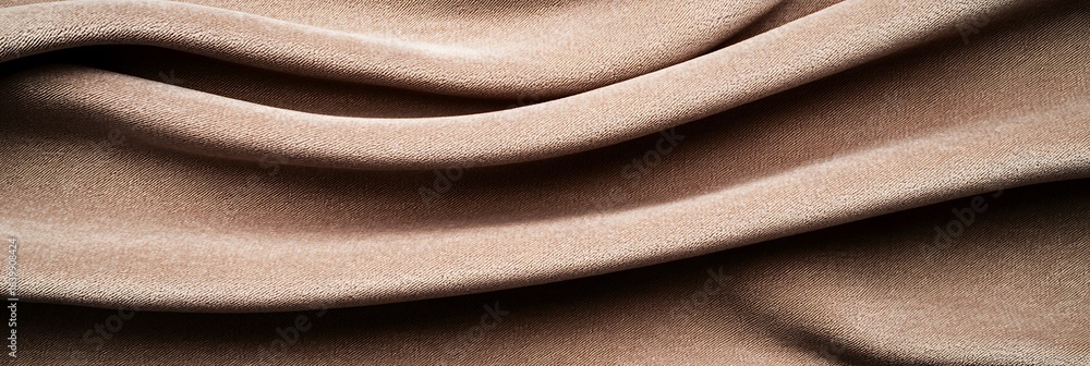 Fototapeta premium Soft, textured fabric drapes elegantly, showcasing its smooth surface and warm beige tones, suggesting comfort and luxury in design.