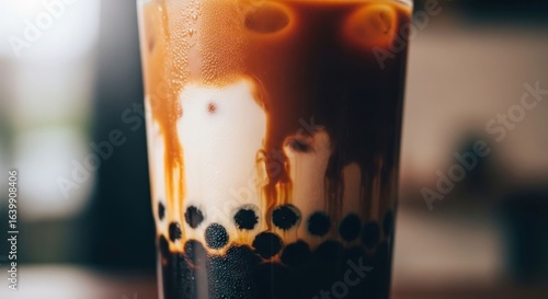 Boba drink in clear cup with dark syrup, milk swirling on surface