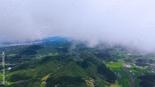 Aerial Drone View of Highway and Cars Driving Through Green Fields and Forest, with Vast Summer Landscape, Blue Sky, and Clouds for a Healing Scenery