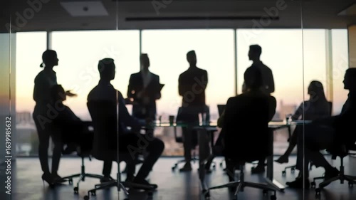 Silhouetted Business Team Collaborating in a Modern Glass Office During a Dramatic Sunset
