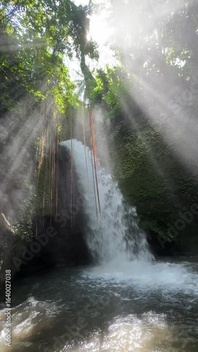 Close up secret Waterfall in the Jungle in sunlight rays near Ubud, Bali view from the bottom