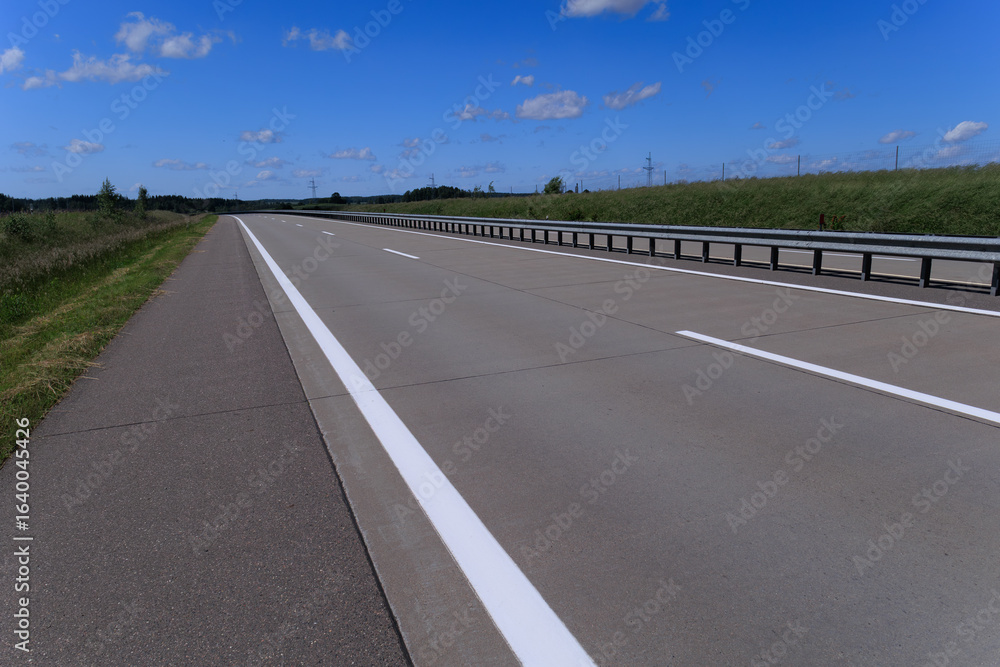 Fototapeta premium Road view on a summer day. Highways and bridge, roadside and white road line markings.