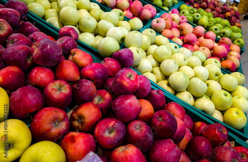 Colorful display of fresh apples in a local market during the morning, showcasing various varieties and vibrant colors in wooden crates
